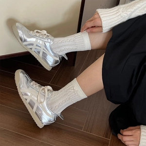 Silver metallic low-top sneakers styled with white knit socks and a black skirt