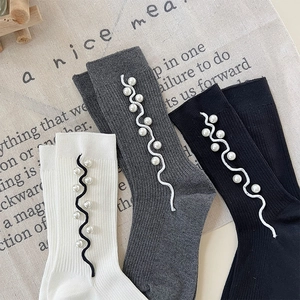 Detail of ribbed knit socks with elegant pearl accents and wavy stitched trim