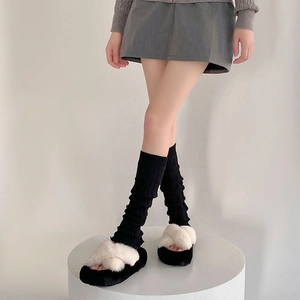 Close-up of women grey knitted slouch socks paired with plush cross-strap slippers