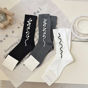 Detail of ribbed knit cotton socks featuring delicate side ruffles and pearl embellishments
