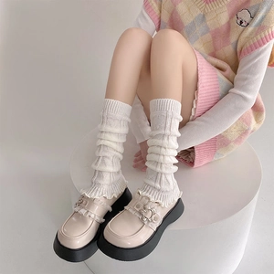 Detail of white knit slouch socks with heart texture and lace trim on Mary Jane shoes