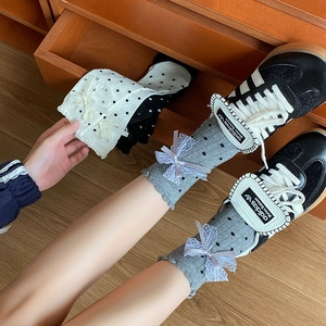 Detailed view of grey and white dot patterned socks with 3D lace bows and wavy cuffs