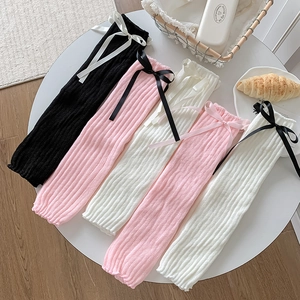 Détails de jambières en maille côtelée avec nœuds en noir, rose et blanc