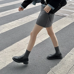 Close-up of black matte platform loafers paired with vertical striped crew socks in city style