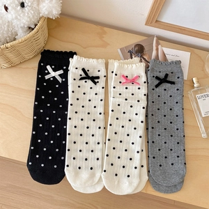 Flat lay of cute polka dot socks with ruffled edges and delicate ribbon bows on wood