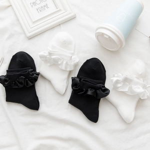Detailed flat lay of white and black crew socks featuring silk ruffled edges and soft knit fabric