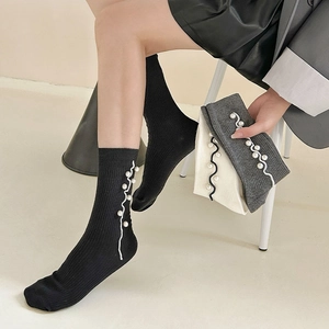 Close-up of ribbed cotton socks featuring elegant pearl beads and wavy trim accents