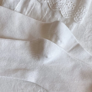 Detailed view of white ribbed knit cotton socks with delicate lace fabric background