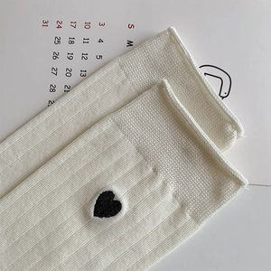 Detail of cream white ribbed knit socks featuring small black heart embroidery