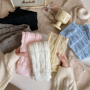 Detail of cable knit leg warmers in various colors with textured heart patterns