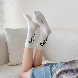Détail de chaussettes en coton blanc avec jacquard à nœud noir et accents de perles