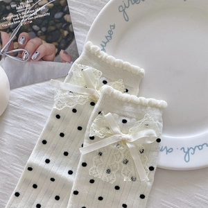 Detail of polka dot socks with ruffled lace trim and delicate translucent bow tie