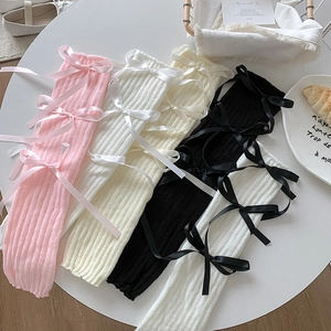 Detailed knit texture and satin bows on four colored leg warmers in a cozy flat lay