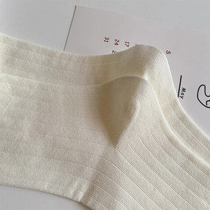 Detail of white ribbed knit socks with vertical stripe texture and soft cream finish