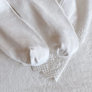 Detail of white cotton socks with vertical ribbed knit and floral lace trim edges