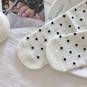 Detail shot of white polka dot socks with lace trim and fine knit texture on fabric