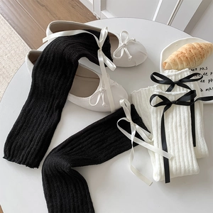 Détail de la texture en maille de jambières avec des nœuds en ruban de soie contrastés