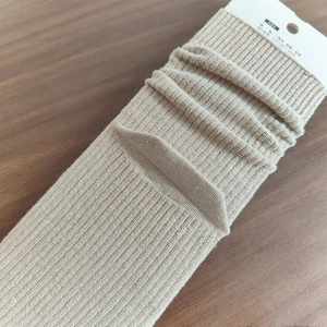 Dettaglio calzini in maglia a coste color avena con etichetta di confezione bianca