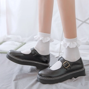 Detail of white ruffle socks with black Mary Jane shoes and contrast stitching