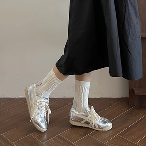 Silver metallic low-top sneakers with reflective finish and classic cross-stripes design