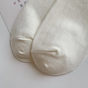 Detailed close-up of fine knit craftsmanship and smooth seamless toe on cream cotton socks