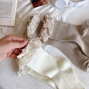 Detail of delicate lace trim and ribbon bow on ribbed cotton socks in Japanese style