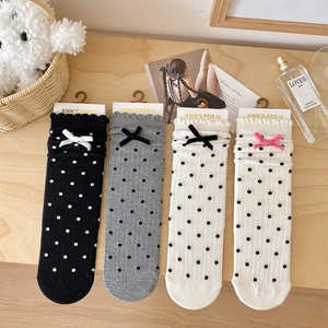 Detail view of four pairs of polka dot socks with bows in black, grey, white and beige