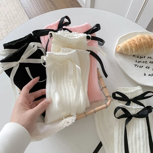 Détail de jambières en tricot noir, rose et blanc avec des nœuds de ruban décoratifs