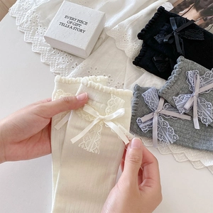 Detail showing lace trim and ribbon bows on knitted socks in white, gray, and black