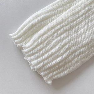 Close-up of white ribbed knit leg warmer detail featuring delicate ruffle edges