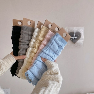 Macro detail of knit leg warmers in various colors featuring cable knit texture and labels