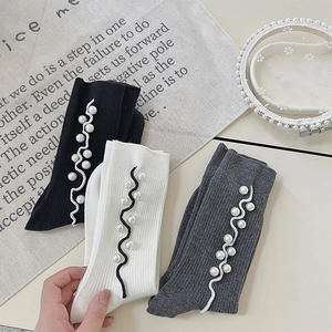 Detail of knit socks with elegant white pearls and delicate wavy trim decorations