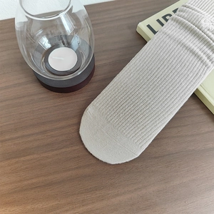 Primo piano dettagliato di calze a coste in maglia beige chiaro su fondo in legno scuro