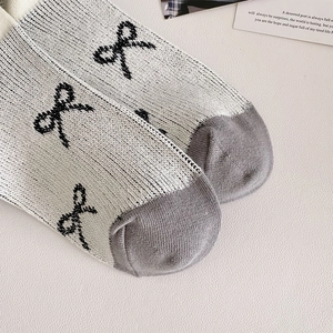 Detail von Ballet-Stricksocken mit schwarzem Bogen-Jacquardmuster und Rippstruktur