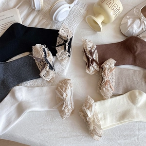 Detailed close-up of multi-color cotton socks with lace trim and satin bows on fabric