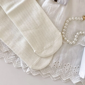 Close-up of cream ribbed knit socks featuring delicate cotton texture and lace background