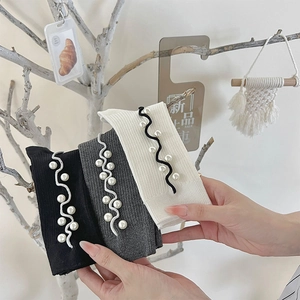 Detailed view of women's ribbed knit socks featuring wavy trim and faux pearl embellishments