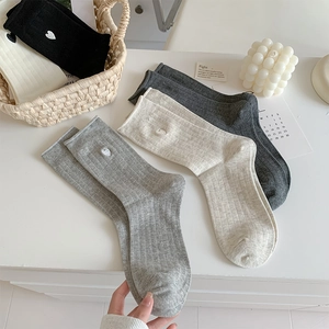Detailed knit texture of striped mid-calf socks with delicate heart embroidery details