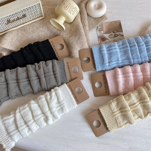 Detail of cable knit leg warmers in various colors with original paper packaging