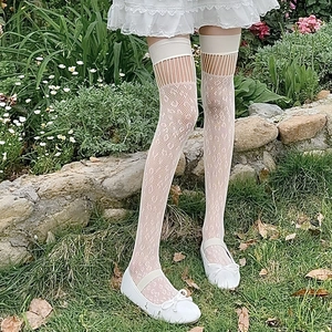 Close-up of white mesh lace over-the-knee stockings with delicate floral patterns