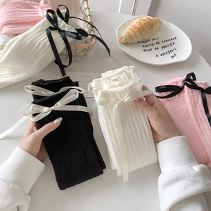 Gros plan sur des jambières en tricot côtelé avec d'élégants nœuds en satin de couleur