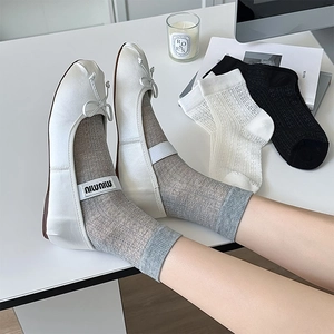 Dettaglio di calze a rete bianche traspiranti abbinate a eleganti ballerine chic