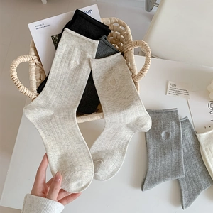 Close-up of heart embroidery detail on vertical striped ribbed cotton crew socks