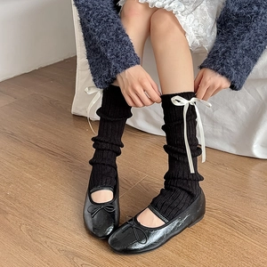 Détail de jambières noires en maille avec nœuds blancs et chaussures Mary Jane