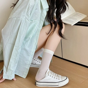 Close-up of white semi-transparent crew socks worn with canvas mule sneakers in a casual style