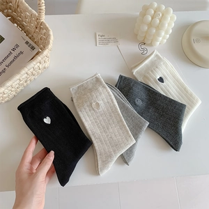 Detailed knit texture of vertical striped socks featuring minimalist heart embroidery