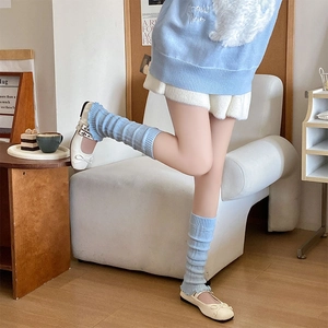 Detail of light blue ribbed knit leg warmers with wavy edges and Mary Jane shoes
