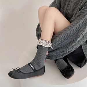 Detail of dark grey ribbed socks featuring creamy lace trim and purple ribbon bows