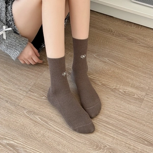 Dettaglio di calze in cotone marrone caffè a coste con ricamo a fiocco bianco sottile