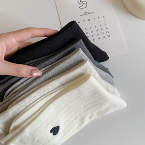 Detailed close-up of embroidered heart on ribbed vertical stripe knit cotton socks